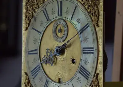 Antikes Zifferblatt einer englischen Standuhr mit aufwendigen Verzierungen und römischen Ziffern.